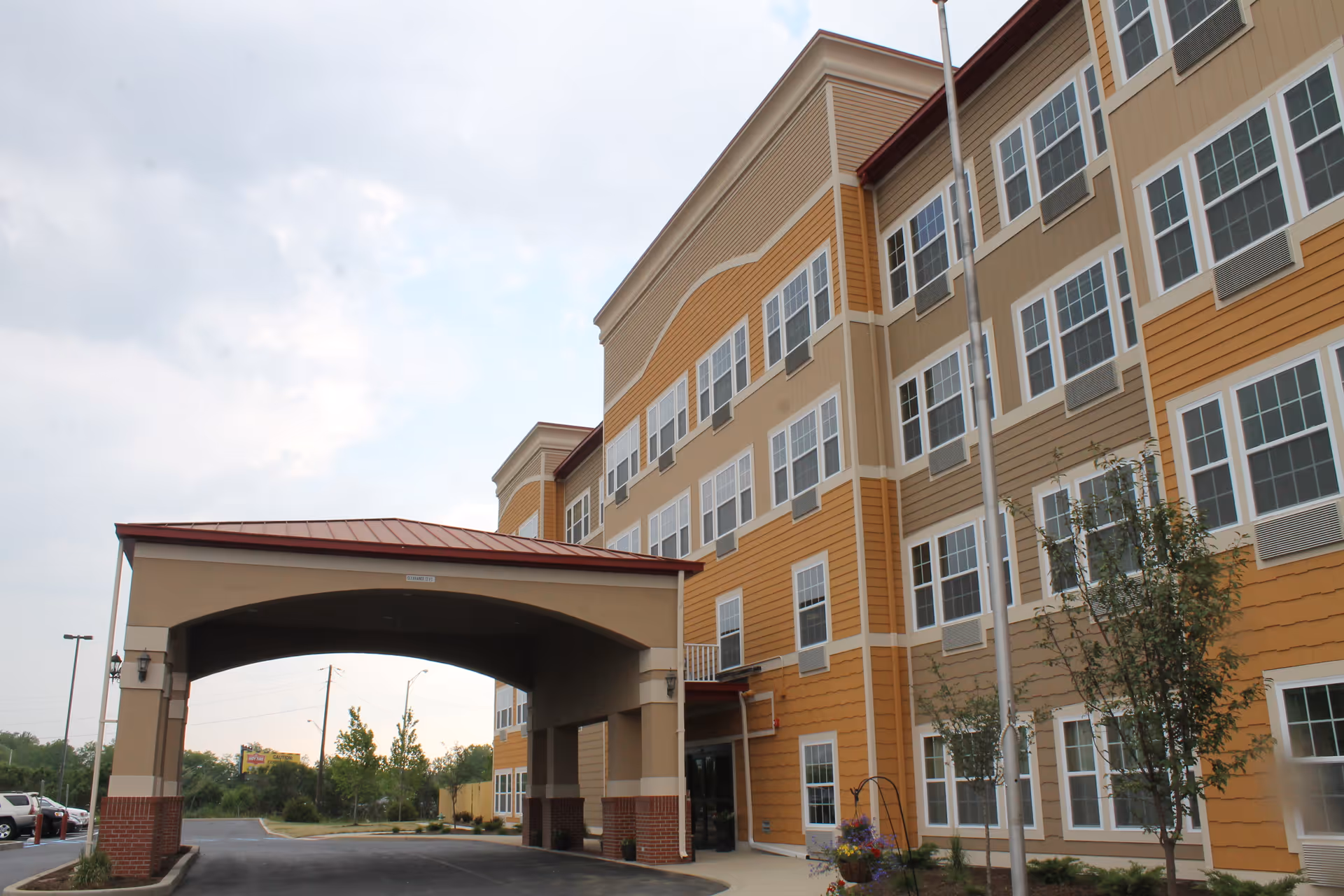 Entrance canopy and front facade of a multi-story senior living building with rows of windows.