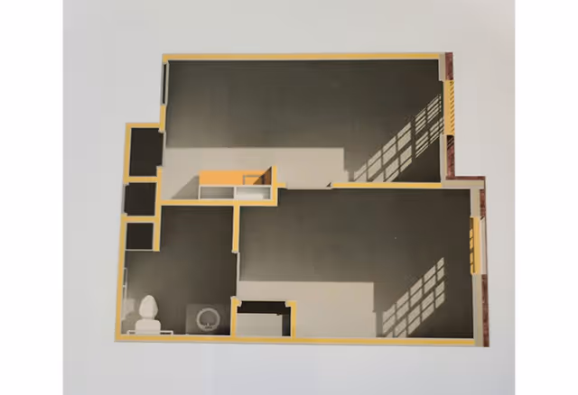 Architectural floor plan of a living space showing multiple rooms including a bathroom with a toilet and sink, and other undefined rooms with windows casting shadows.