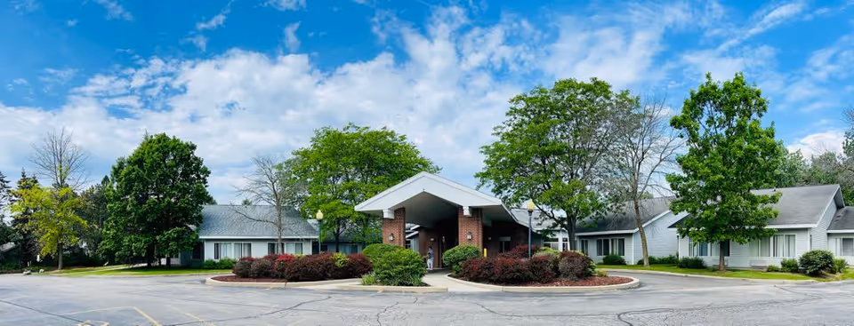 Front exterior view of Glendale Care and Rehab Center showing a single-story building with a covered entrance, surrounded by trees and landscaped bushes under a partly cloudy sky.