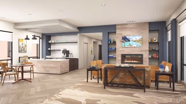 Modern senior living common area with seating, fireplace, a wall-mounted TV, and a kitchenette/bar.