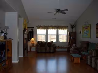 A cozy senior living common living room with sofas, chairs, and a large window.
