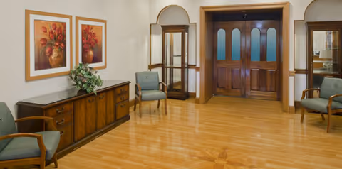 Courtland facility lobby with wooden floors, chairs, artwork, and arched doorways.