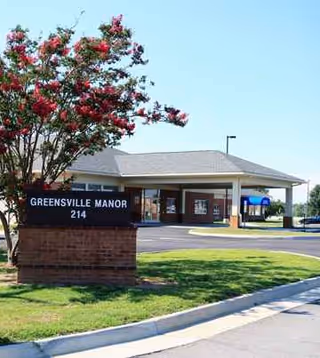 Exterior view of Greensville Manor entrance with sign and covered drop-off area.