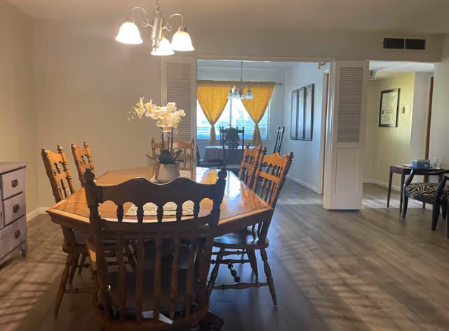 Spacious dining room featuring a wooden table, chairs, and a vase centerpiece.