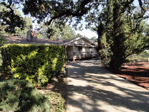 Front view of a ranch-style senior living facility with a walkway and trees.