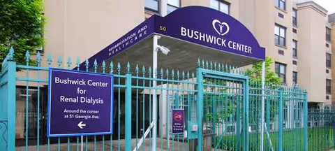 Front entrance of Bushwick Center with teal fence and blue signage.
