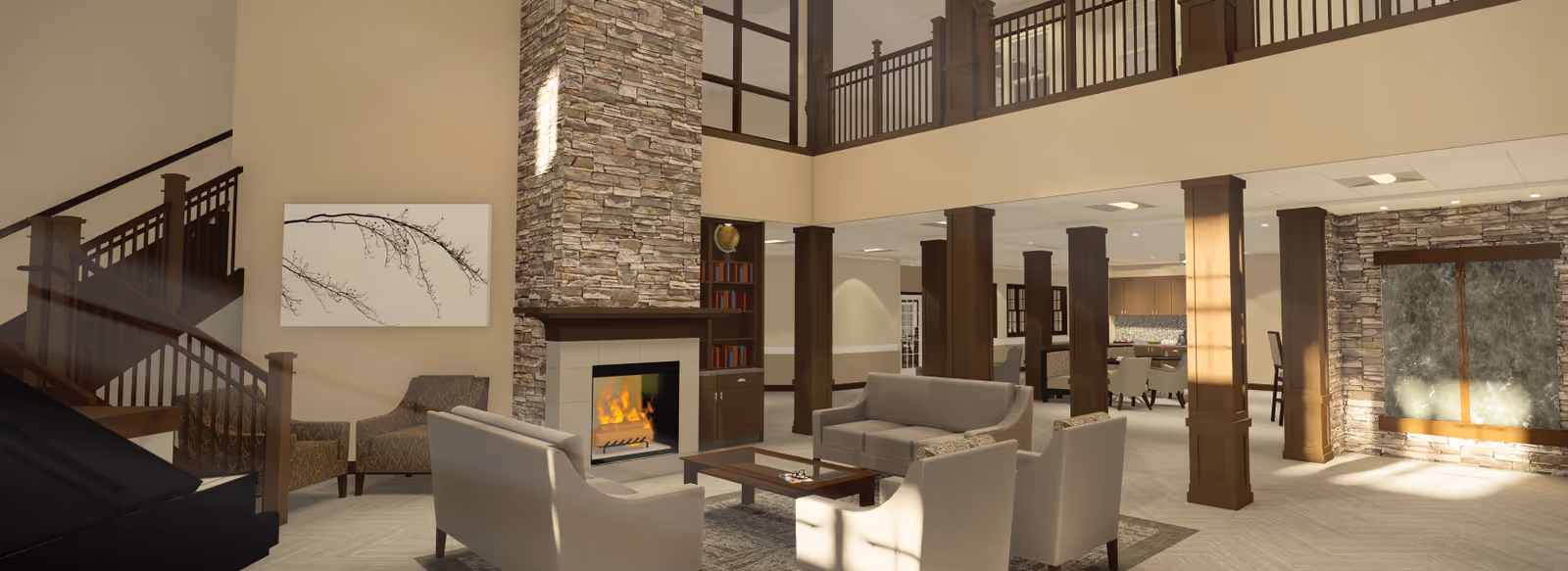 A spacious and well-lit living room area with high ceilings and a second-floor balcony overlooking the space. The room features a stone fireplace with a fire burning, surrounded by built-in shelves with books. There are multiple seating options including sofas and armchairs arranged around a coffee table. The walls are painted beige, and there is a large piece of artwork above a chair near the staircase. The room has wooden columns and railings, and sunlight streams in through windows, creating a warm and inviting atmosphere.