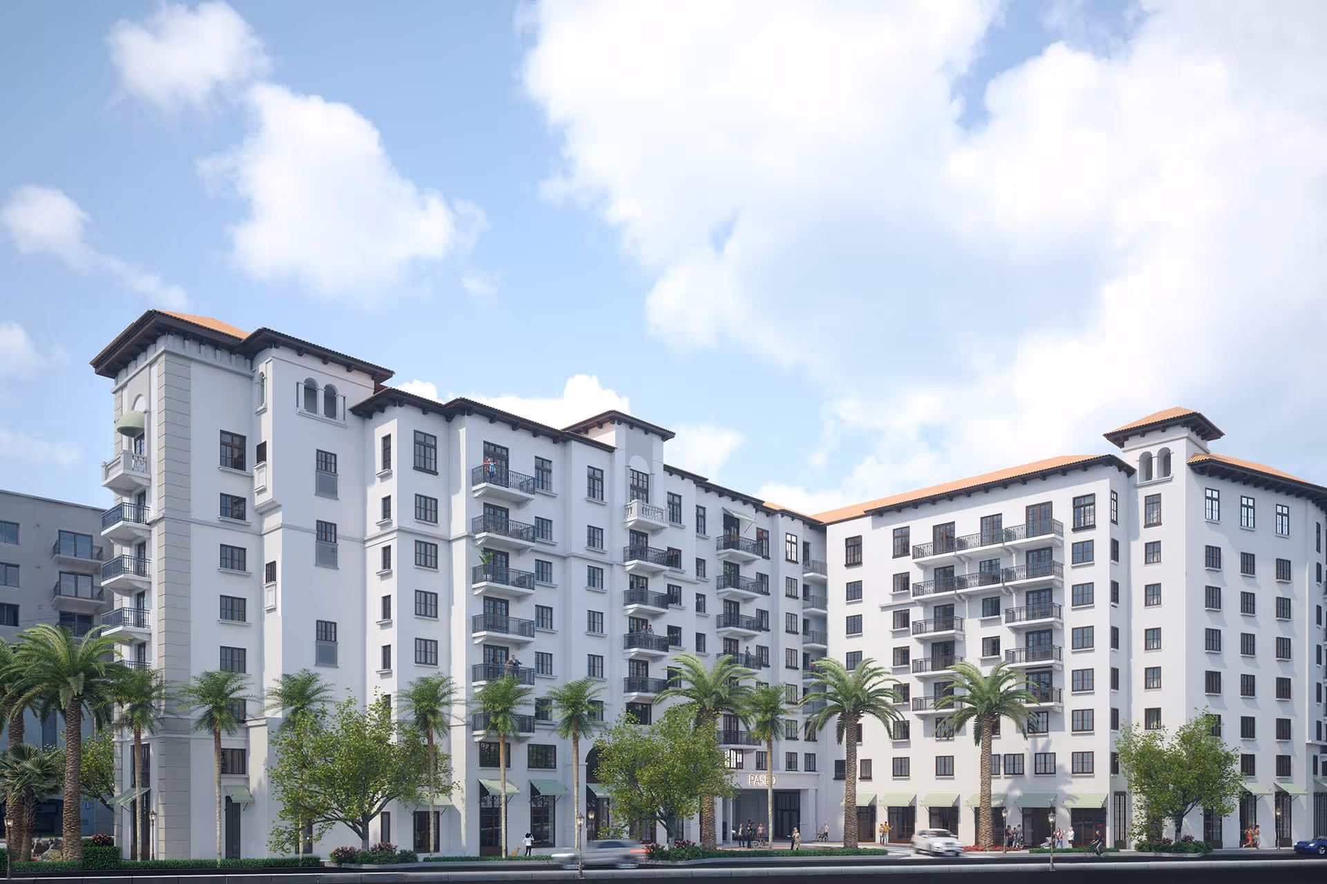 Exterior view of a large, multi-story senior living facility with white walls, numerous balconies, palm trees, and a clear blue sky with some clouds.