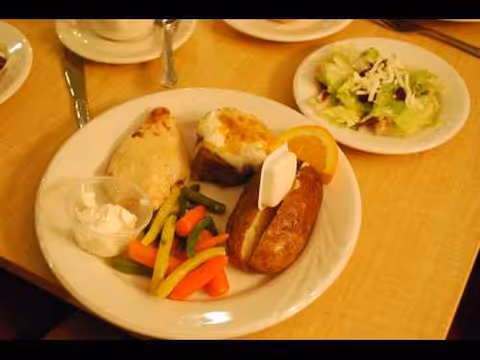 Plate with assorted foods and side salad on a dining table.
