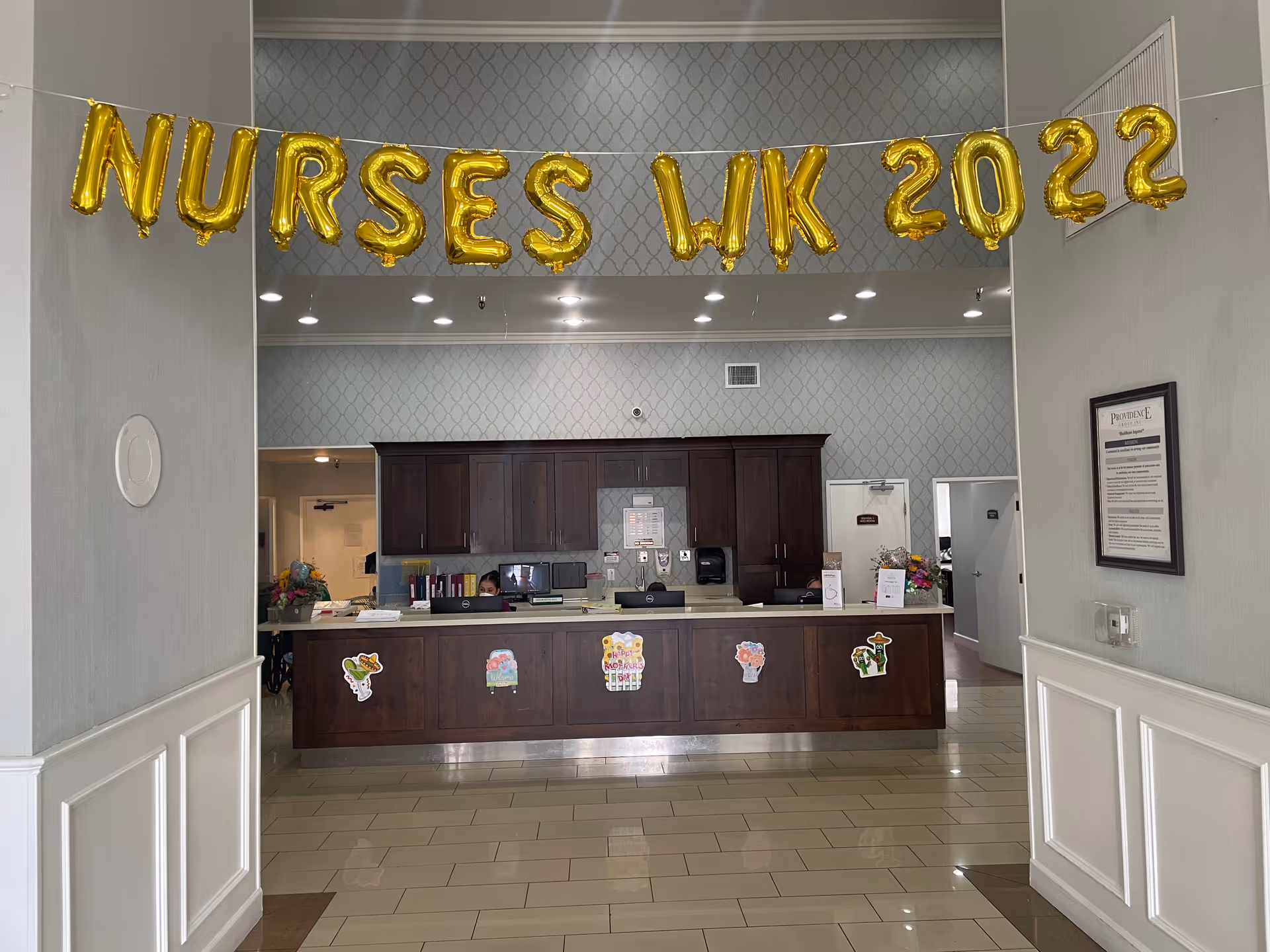 Lobby reception desk decorated with gold 'NURSES WK 2022' balloons over the counter.