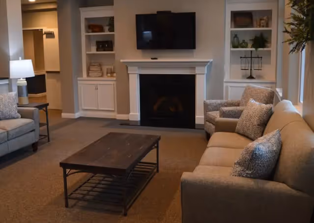 Cozy living room with sofa, armchairs, coffee table, fireplace, and built-in shelves.