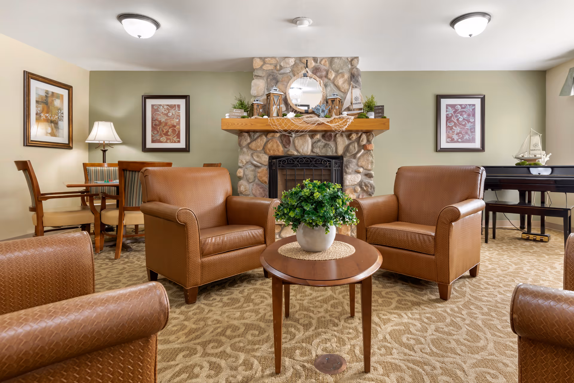 Cozy seating area with leather armchairs around a coffee table in front of a stone fireplace and decorated mantle.