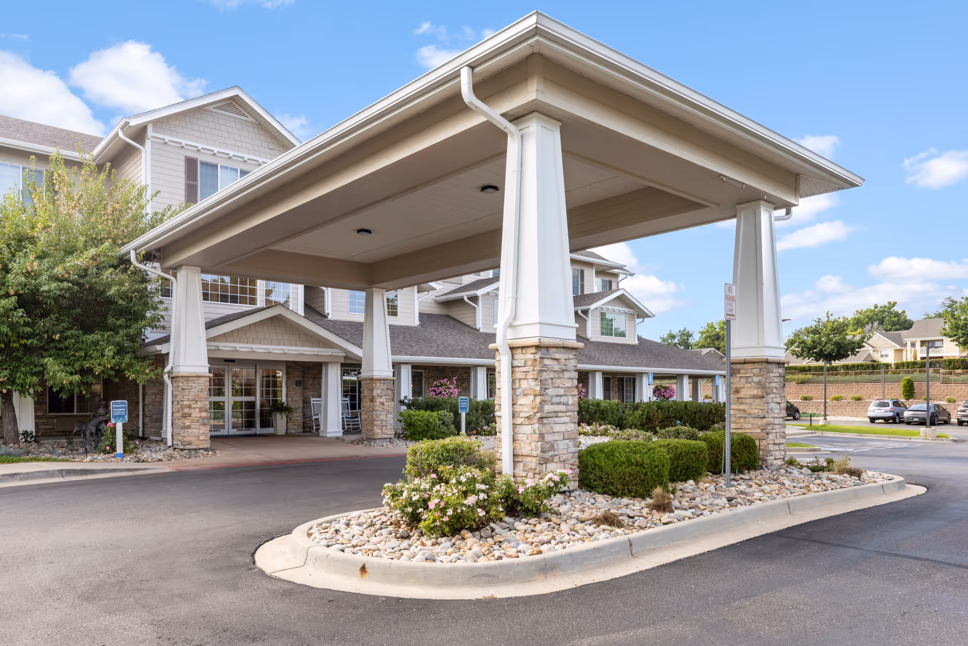 Covered porte-cochere and landscaped drop-off area at the front entrance of a senior living building.