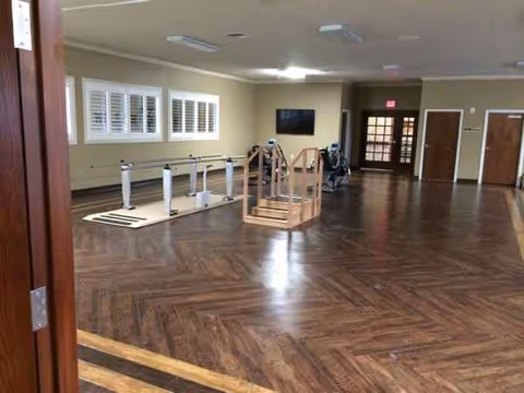 Willow Park Rehabilitation and Care Center rehab room with parallel bars and wooden floors.