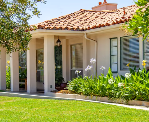 Front exterior of Villa Alamar facility with tiled roof, columns, and lush garden.