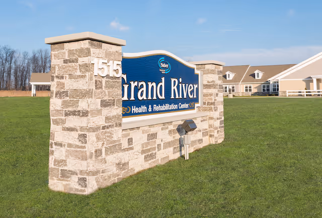 Stone entrance sign reading 'Grand River Health & Rehabilitation Center' with the number '1515' on a grassy lawn and the facility building visible in the background.