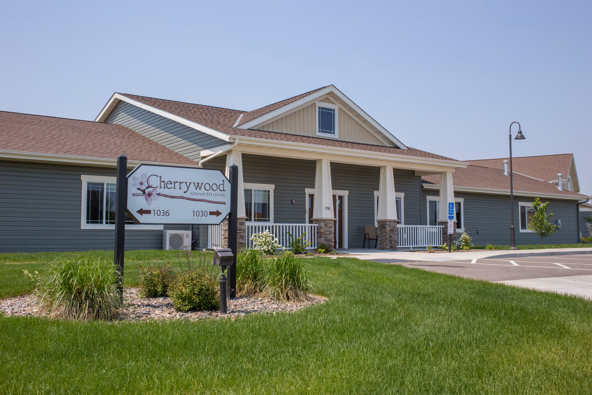 Single-story Cherrywood Advanced Living facility in St. Cloud, MN with a covered front entrance and a sign on the lawn.