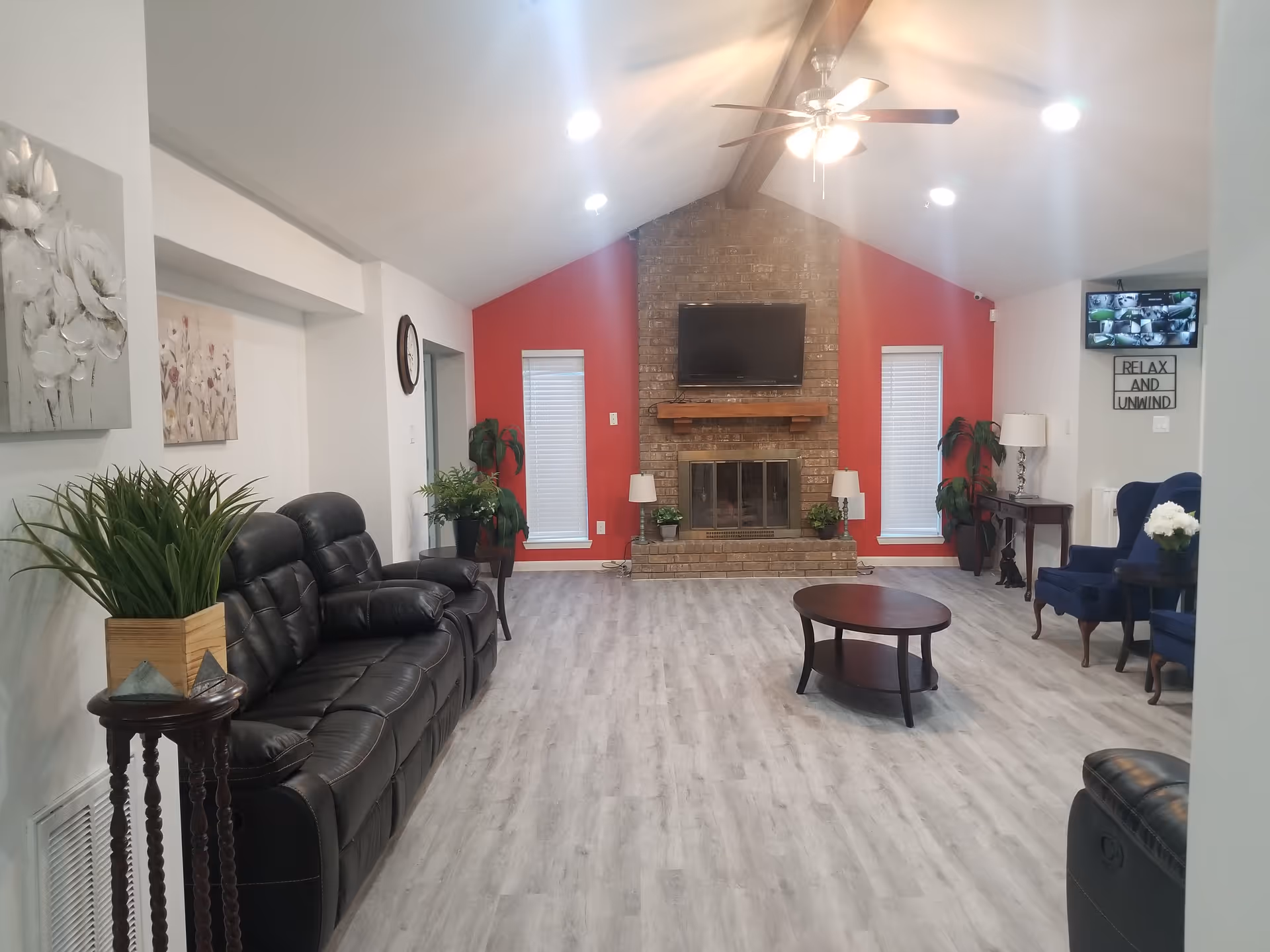 Bright living room with leather sofa, brick fireplace, TV, and red accent wall.