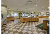 Spacious dining area with multiple buffet stations, checkered tile floor, and overhead lighting.