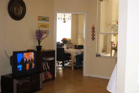 Cozy living room at Golden House Assisted Living with TV and doorway to dining.