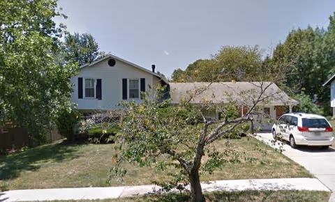 Exterior view of Adelphi House I, a single-story building with a driveway and parked car.