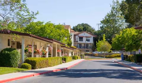 Exterior view of Atterdag Village of Solvang with a covered walkway and greenery.