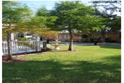 Grassy courtyard with trees, a central fountain, white gazebo-style railing, and surrounding low-rise building.