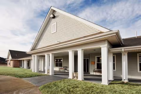 Senior living facility exterior with a covered front porch and white columns.