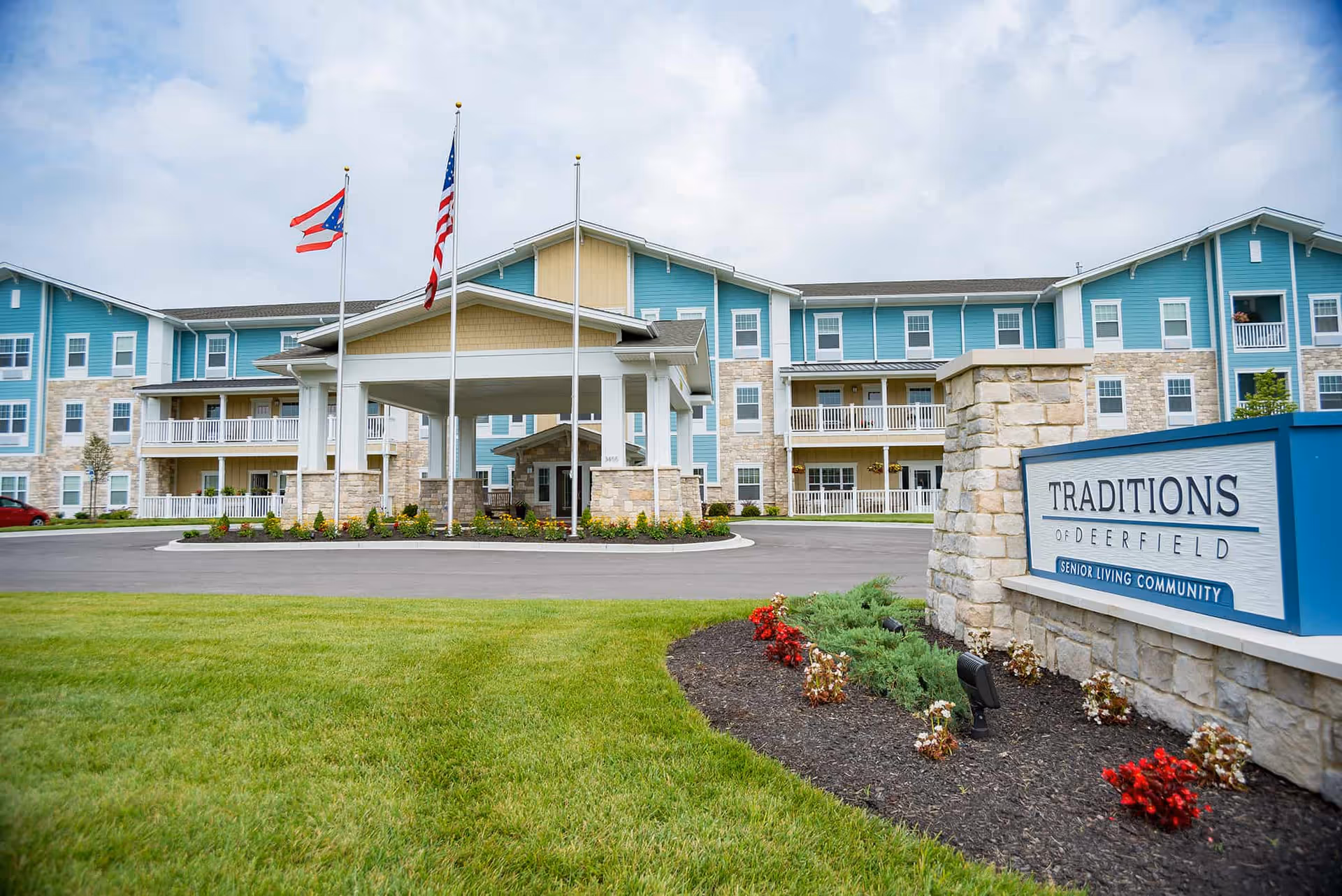 A senior living facility named Traditions of Deerfield with a well-maintained exterior and landscaped gardens.
