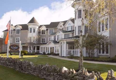 Exterior of Bickford of Upper Arlington senior living facility with lawn and flagpoles.