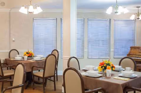 A dining room with tables set for meals and floral centerpieces.