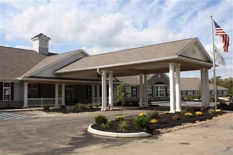 The Laurels of Athens facility exterior with covered entrance, flag, and landscaped bed.