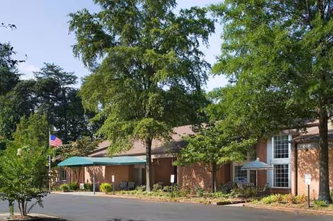Brick senior living facility exterior with trees and a covered entrance