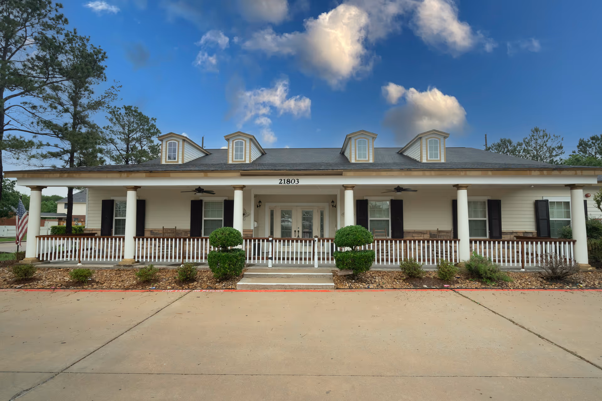 Single-story ranch-style building with a long porch and trimmed shrubs.