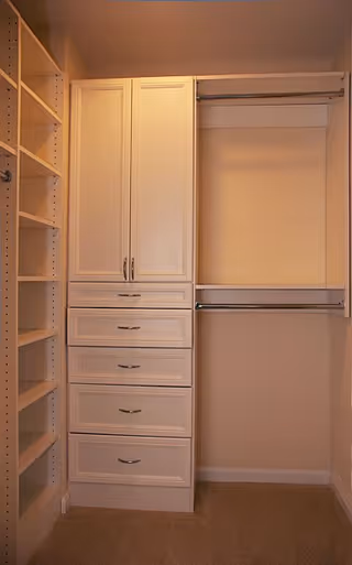 A walk-in closet with built-in white shelving, drawers, and dual hanging rods.