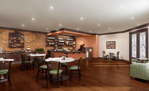 A spacious dining area with wooden floors and multiple round tables with chairs featuring green cushions. The back wall has a brick design with shelves holding various items and a counter area, possibly for serving food or beverages. There are decorative elements on the walls and a pair of glass doors with intricate designs on the right side.