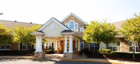 Exterior view of Brookdale Westampton with a covered entrance, columns, and surrounding trees.