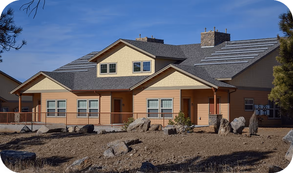 A single-story senior living facility with beige exterior and rocky front yard landscaping.