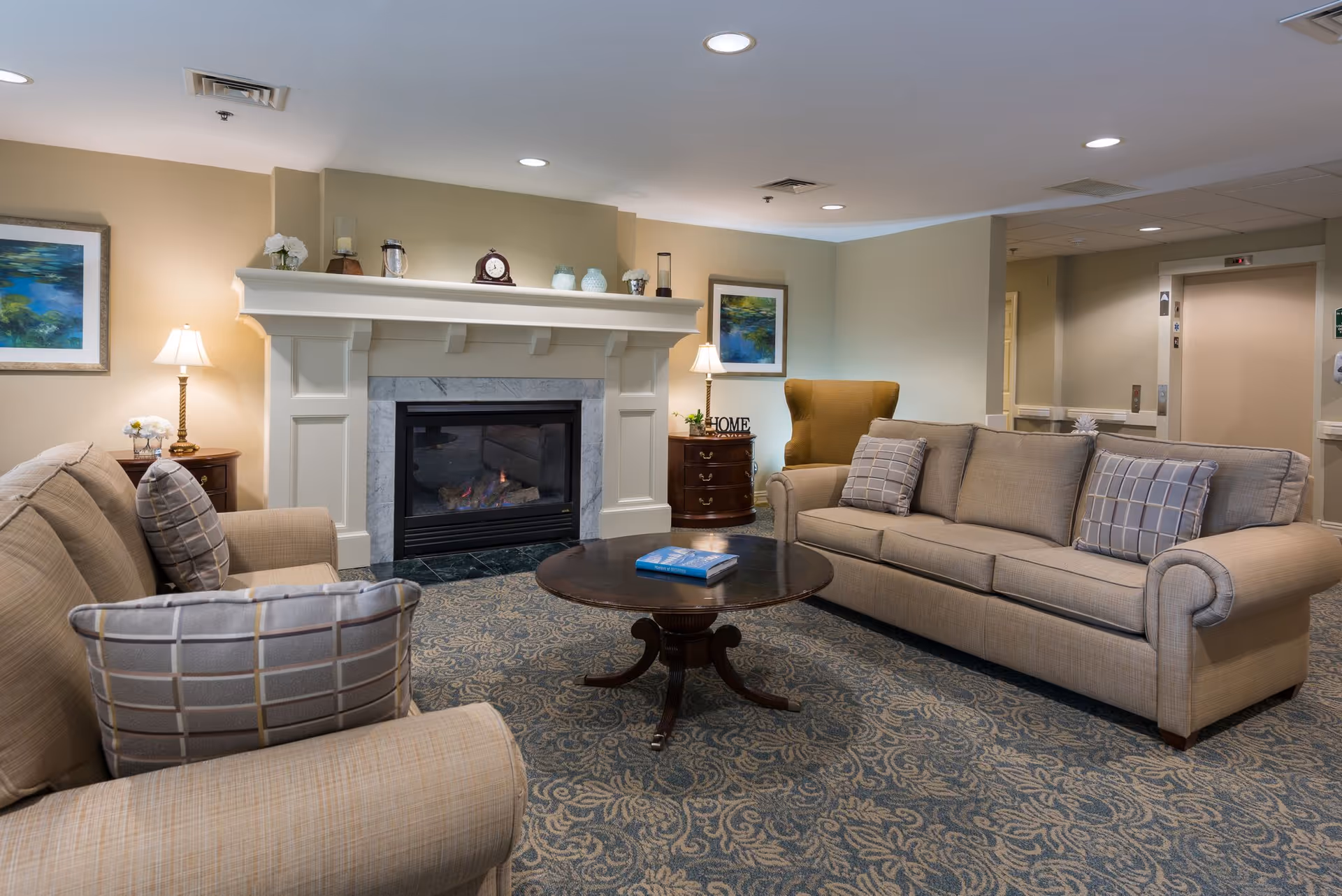 Cozy common living room with sofas, an armchair, a coffee table, and a fireplace mantel.