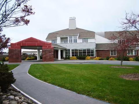 Exterior view of Kendal at Ithaca building with brick entrance and green lawn.