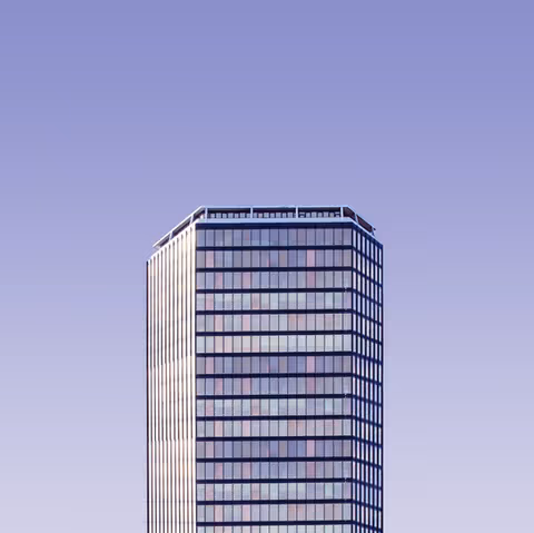 Tall glass office building against a purple gradient sky.