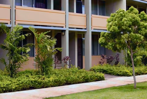 Exterior view of Kukui Gardens senior living facility with balconies, walkway, and landscaping