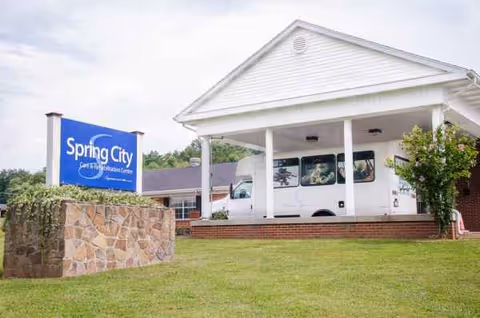 Front view of Spring City Care and Rehabilitation Center with a white van under a portico.