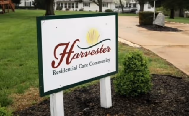 A yard sign reading 'Harvester Residential Care Community' in front of a residential building.