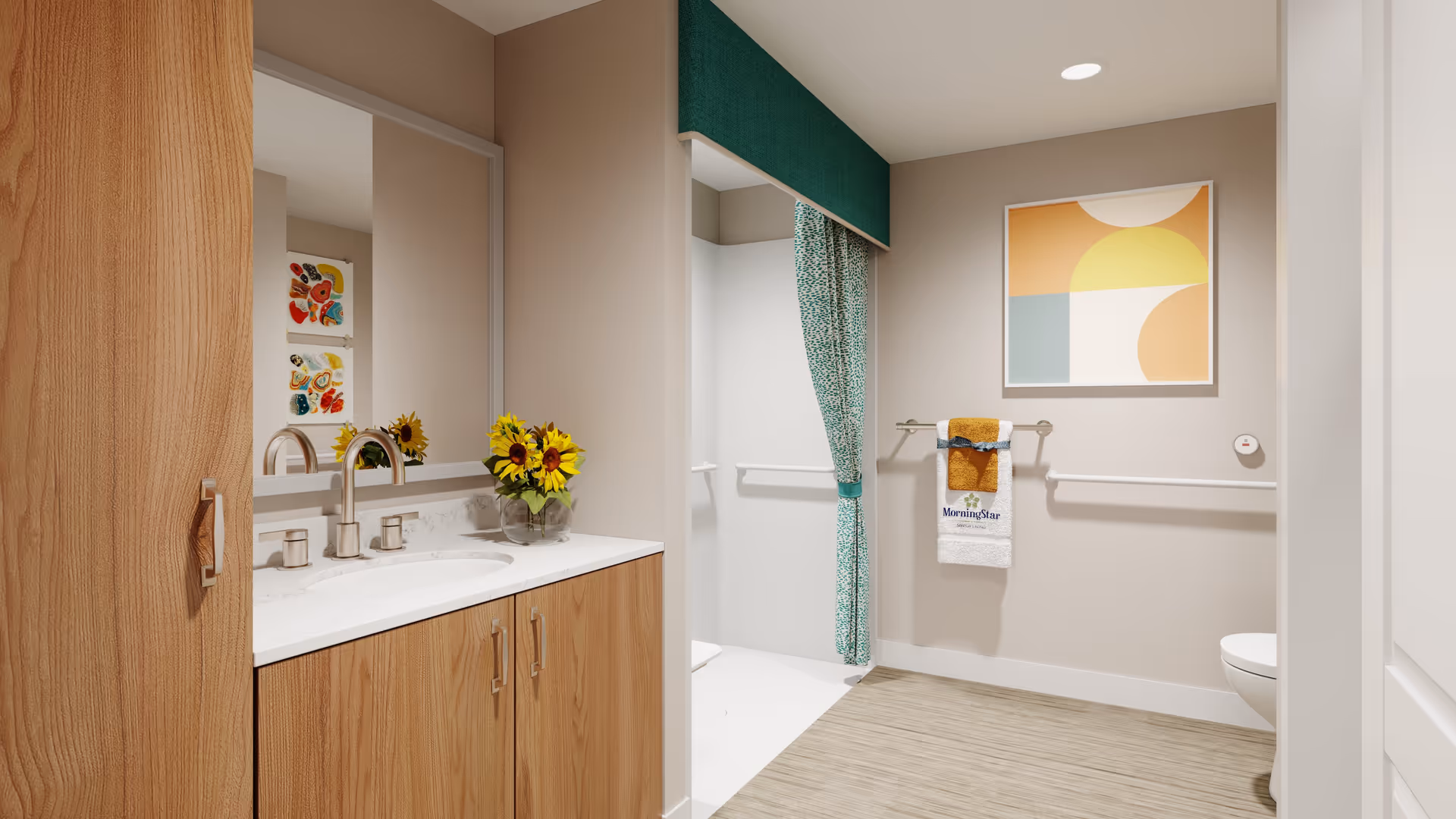 A modern bathroom with a wooden vanity featuring a white countertop and a sink. A vase with sunflowers is placed on the countertop. There is a large mirror above the sink. To the right, there is a walk-in shower with a green patterned curtain and a green valance. A towel rack holds a white towel with the MorningStar logo and a mustard yellow towel. The walls are beige, and there is a colorful abstract painting hanging above the towel rack. The floor has a light wood texture.