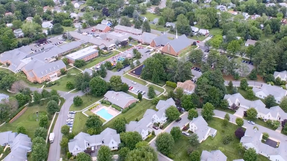 Aerial view of the Wiley Christian Retirement Community campus showing multiple residential buildings, a swimming pool, parking areas and surrounding trees.
