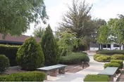 Outdoor courtyard with benches, paved walkways, and trimmed shrubs.