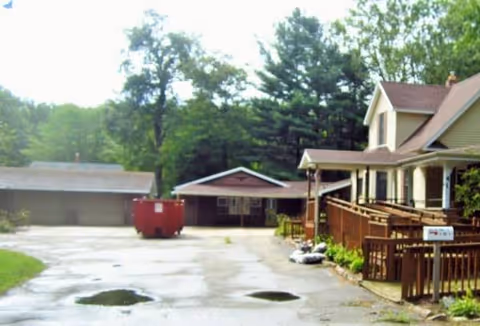 Exterior view of Dudley Retiree Home with ramp, fence, and dumpsters.