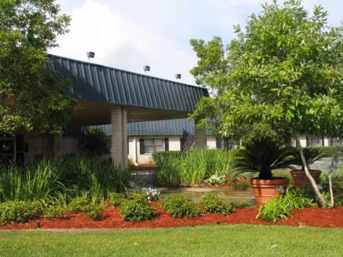 Front exterior of Baton Rouge Health Care Center with landscaped grounds and entrance.