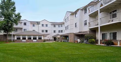 Exterior view of a multi-story senior living building surrounding a green grassy courtyard.